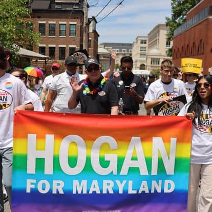 The image is from the June 2024 Annapolis Pride Parade. People are holding a Larry Hogan for Maryland sign. 